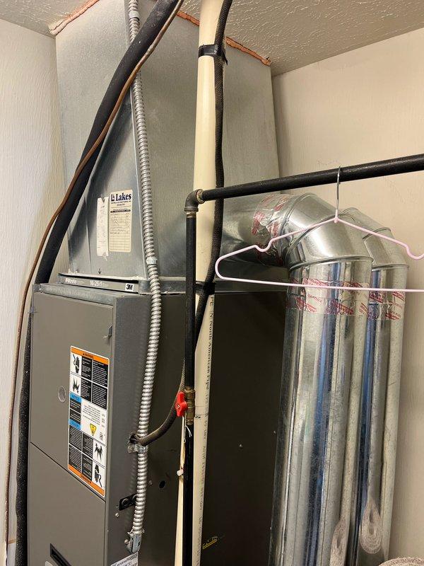 Completed air conditioning retrofit installation in residential utility space. Existing Lennox Elite furnace system assessed and integrated with new A/C components, including refrigerant line connections, condensate drainage via PVC piping, and electrical controls. All mechanical connections secured and system tested for proper operation with existing HVAC infrastructure.