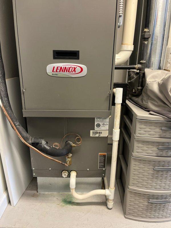 Completed air conditioning retrofit installation in residential utility space. Existing Lennox Elite furnace system assessed and integrated with new A/C components, including refrigerant line connections, condensate drainage via PVC piping, and electrical controls. All mechanical connections secured and system tested for proper operation with existing HVAC infrastructure.