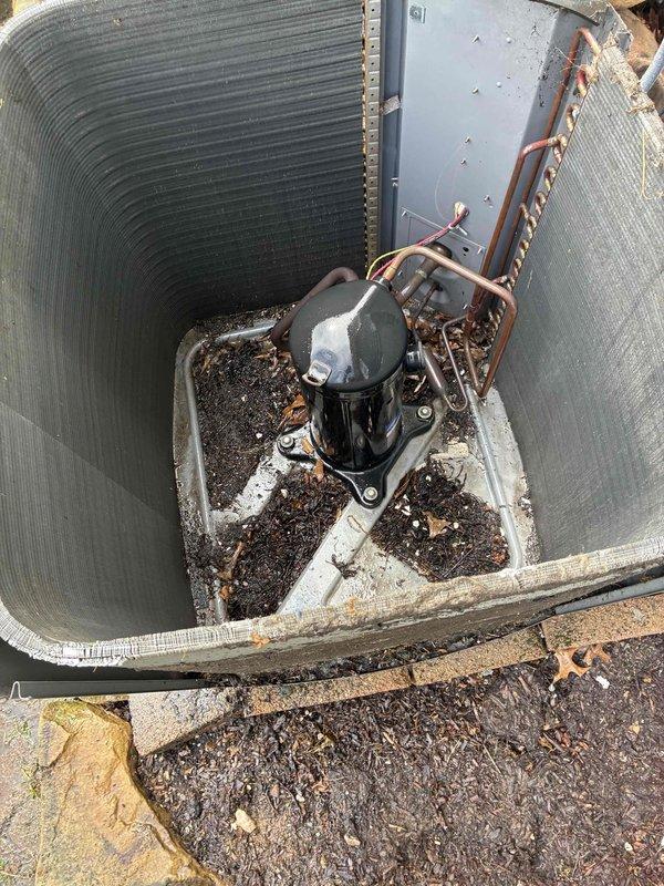 Performed preventive maintenance on 20+ year old air conditioning system. Inspected outdoor condensing unit located in below-grade corrugated metal enclosure, removed accumulated leaves and organic debris from concrete pad and unit perimeter, and checked refrigerant line insulation condition. Evaluated indoor ductwork system with reflective insulation wrapping and verified proper mechanical connections throughout the installation.