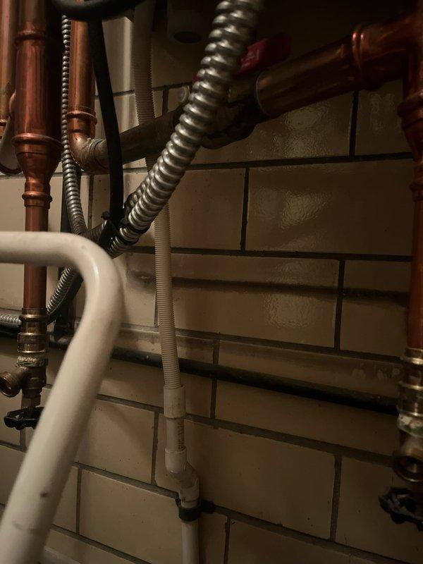 Completed boiler retrofit involving the replacement of an existing Triangle Tube boiler unit. Installation included reconnection of copper supply lines, flexible metallic hoses, and integration with existing PVC drainage system, ensuring all plumbing connections were properly secured and tested for system functionality.