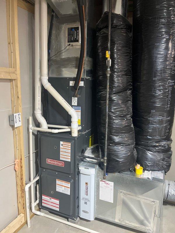 Completed comprehensive site evaluation for AC retrofit and equipment sizing analysis. Documented existing HVAC system consisting of Goodman furnace/air handler unit and CAPF3636B2DB evaporator coil rated for R22 or R410A refrigerant with 450 PSIG design pressure. Photographed manufacturer data plates, mechanical room configuration, ductwork layout including large black flexible ducts, and condensate drain piping. Assessed installation conditions in basement mechanical space with concrete flooring to determine proper equipment specifications for replacement system.