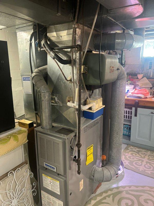 Completed air conditioning retrofit installation in residential basement mechanical room. Installed Tempstar furnace unit with associated ductwork modifications, including galvanized metal plenum connections and flexible duct runs to integrate with existing HVAC distribution system. System tested and operational upon completion.