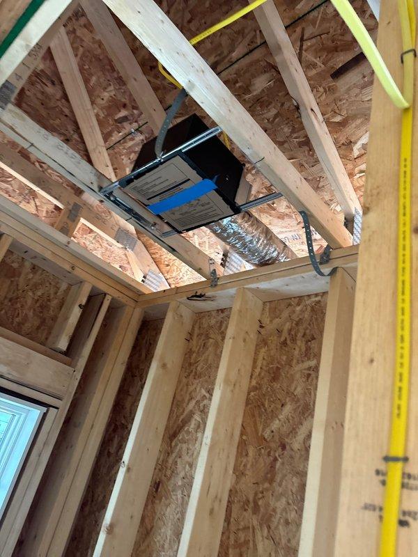 Completed rough-in installation of bathroom exhaust fans and connected return air pan in basement area of new construction project. Installed flexible ductwork routing through ceiling joists and framed cavities, integrating HVAC components with existing structural framework and coordinating with electrical rough-in. All ventilation connections secured and positioned for final trim-out phase.
