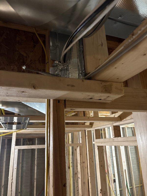 Completed rough-in installation of bathroom exhaust fans and connected return air pan in basement area of new construction project. Installed flexible ductwork routing through ceiling joists and framed cavities, integrating HVAC components with existing structural framework and coordinating with electrical rough-in. All ventilation connections secured and positioned for final trim-out phase.
