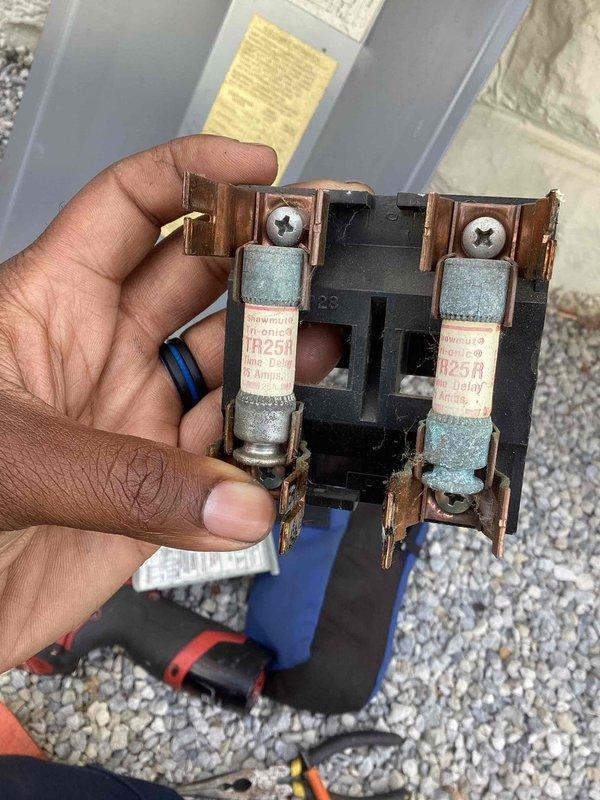 Responded to no-cooling call on 15-year-old Carrier AC system. Upon arrival, found unit completely inoperative. Inspected electrical disconnect and discovered heavily corroded TR25R fuses with significant copper oxidation and turquoise-green patina on metal end caps, indicating prolonged moisture exposure. Corrosion on fuse terminals and copper clips prevented proper electrical contact. Replaced failed fuse assembly with new disconnect fuses rated to manufacturer specifications. Verified proper electrical connections and tested system operation. Unit restored to full cooling capacity with normal amperage draw and proper system function confirmed.
