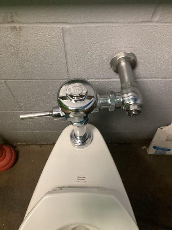 Responded to service call for non-flushing toilet in service bathroom with reported cracking. Upon inspection, found wall-mounted flush valve toilet system with damaged porcelain fixture requiring replacement. Removed existing cracked toilet bowl and wall-mounted chrome flush valve assembly. Installed new white porcelain toilet fixture with updated flush valve hardware and supply line connections. Tested flush mechanism for proper operation and verified all connections for leaks. System restored to full working order with new hardware installed.