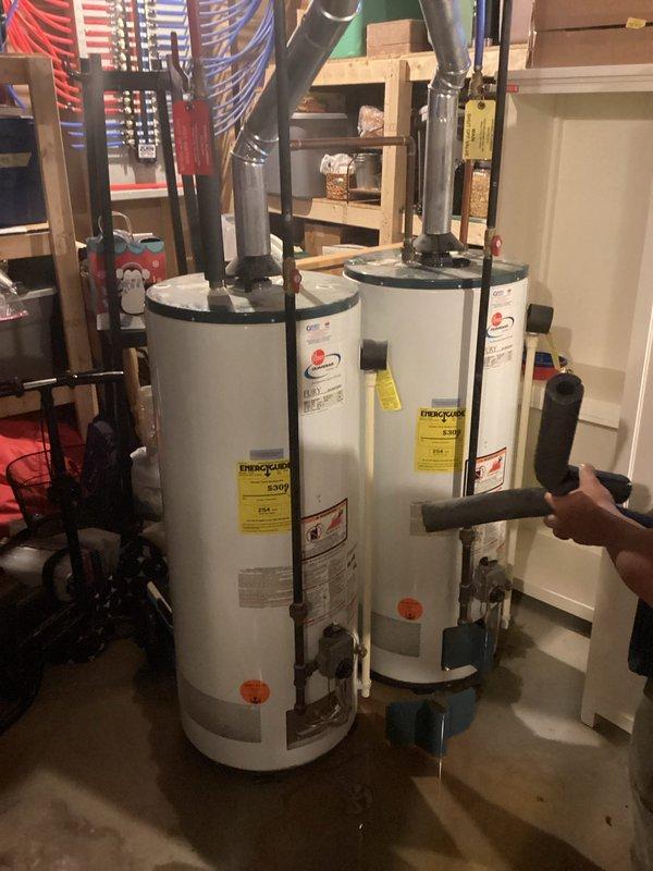 Responded to service call for water heater leaking from top connections. Upon inspection, identified two water heaters installed in basement utility room with active leak originating from upper pipe connections on one unit. Documented existing conditions with photographs showing water staining on concrete floor around base of affected heater. Evaluated both units, associated piping, valves, and fittings to determine source of leak and assess overall system condition. Provided estimate for necessary repairs to address leaking connections and prevent further water damage to surrounding area.