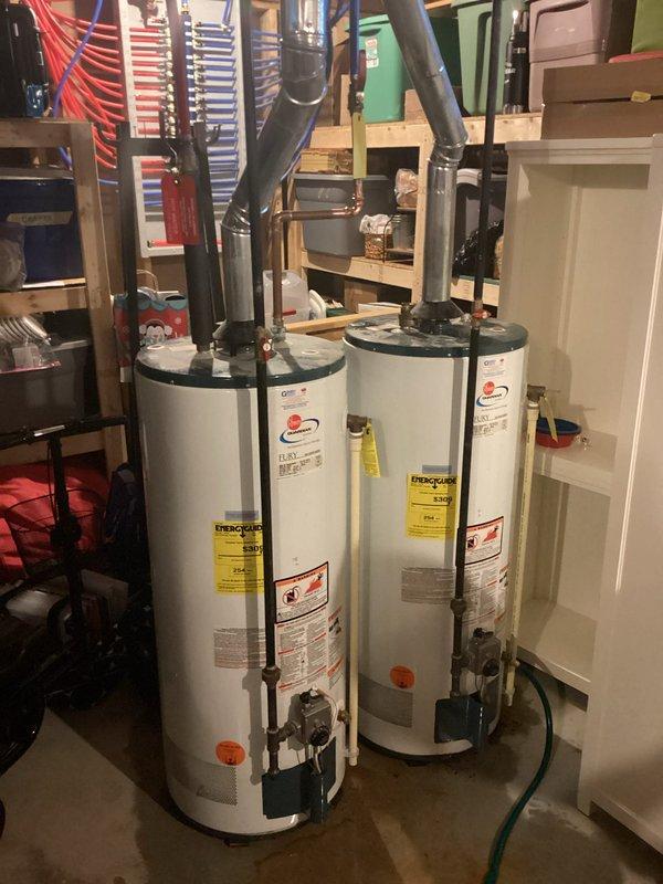 Responded to service call for water heater leaking from top connections. Upon inspection, identified two water heaters installed in basement utility room with active leak originating from upper pipe connections on one unit. Documented existing conditions with photographs showing water staining on concrete floor around base of affected heater. Evaluated both units, associated piping, valves, and fittings to determine source of leak and assess overall system condition. Provided estimate for necessary repairs to address leaking connections and prevent further water damage to surrounding area.