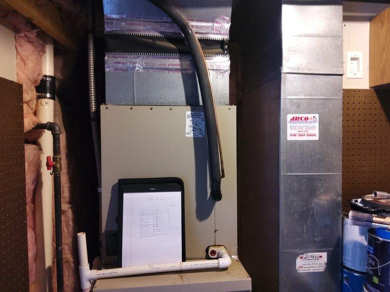 Completed full HVAC system retrofit installation in residential basement utility area. Installed new Lennox Merit Series gas furnace with associated white PVC venting and condensate drainage piping, along with metallic ductwork and air handler components. Connected copper refrigerant lines with shut-off valves, routed black flexible conduit for electrical connections, and integrated system with existing infrastructure between exposed wall studs with fiberglass insulation.
