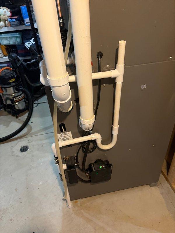 # AC Retrofit Installation

Completed a comprehensive AC retrofit installation in residential basement utility room. Installed new Lennox furnace system with integrated evaporator coil unit and connected all necessary ductwork to existing HVAC infrastructure. Ran black flexible conduit and refrigerant lines from outdoor condensing unit to indoor air handler, ensuring proper insulation and secure mounting. Installed electrical disconnect panel with appropriate labeling and wiring diagrams for code compliance. Connected white PVC condensate drain lines with proper pitch and trap configuration, routing to floor drain with auxiliary condensate pump for backup protection. Mounted all equipment on existing tile floor with proper clearances for service access and airflow. Verified all electrical connections, tested system startup and operation, confirmed proper refrigerant charge and airflow through supply ductwork. System operational and performing to manufacturer specifications.