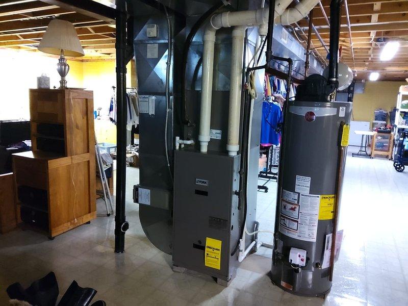 Completed comprehensive AC retrofit in basement utility area. Evaluated existing HVAC infrastructure including York furnace system with PVC venting and assessed compatibility with new air conditioning components. Documented pre-installation conditions of mechanical room layout, including water heater placement, ductwork configuration, and available clearances for equipment installation to ensure proper sizing and positioning of new AC system components.
