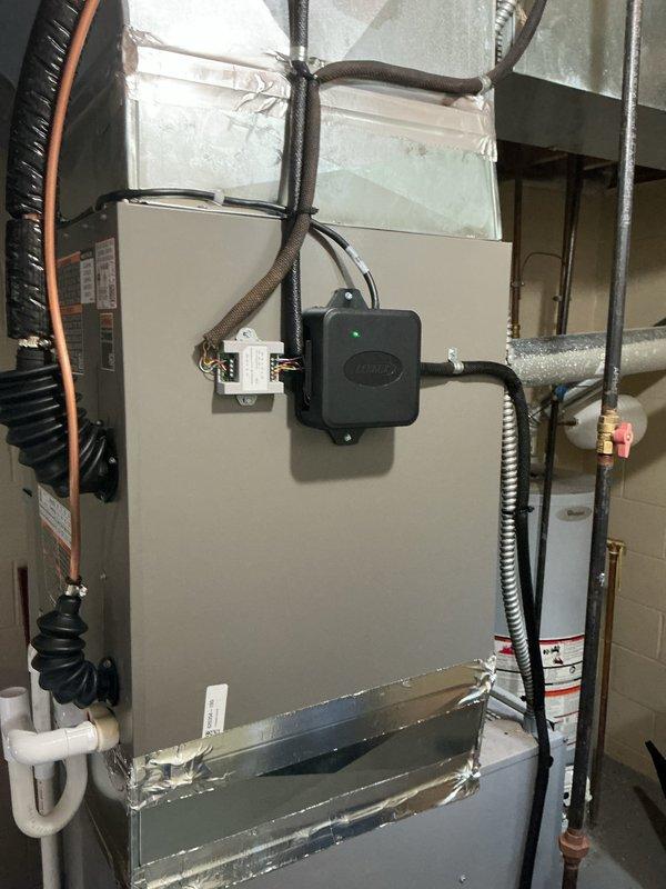 # AC Retrofit Installation

Completed full air conditioning system retrofit including new indoor evaporator coil and outdoor condensing unit. Installed Carrier air handler with integrated control module in basement mechanical room, properly mounting unit to wall with secure support. Routed and connected copper refrigerant lines between indoor and outdoor components, ensuring proper insulation and secure fastening. Installed flexible metal conduit for electrical connections and white PVC condensate drain lines with appropriate pitch for proper drainage.

Positioned new outdoor condensing unit on black rubber mounting pad over white gravel base against exterior wall with adequate clearance for airflow and service access. Mounted electrical disconnect box on exterior wall and completed all electrical connections per manufacturer specifications. Connected refrigerant lines through wall penetration with proper sealing. Integrated new equipment with existing ductwork system, ensuring proper 