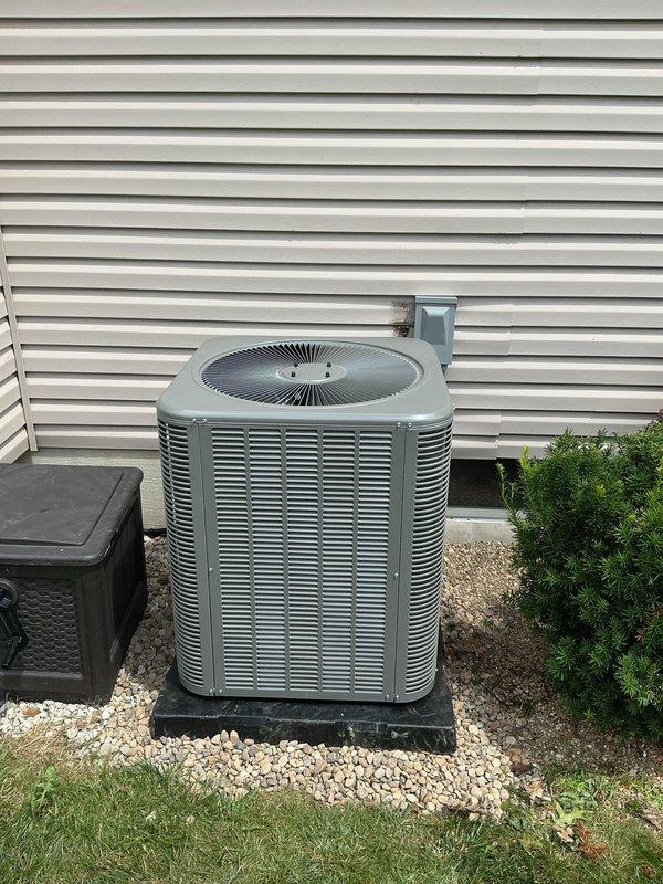 # AC Retrofit Installation

Completed full air conditioning system retrofit including new indoor evaporator coil and outdoor condensing unit. Installed Carrier air handler with integrated control module in basement mechanical room, properly mounting unit to wall with secure support. Routed and connected copper refrigerant lines between indoor and outdoor components, ensuring proper insulation and secure fastening. Installed flexible metal conduit for electrical connections and white PVC condensate drain lines with appropriate pitch for proper drainage.

Positioned new outdoor condensing unit on black rubber mounting pad over white gravel base against exterior wall with adequate clearance for airflow and service access. Mounted electrical disconnect box on exterior wall and completed all electrical connections per manufacturer specifications. Connected refrigerant lines through wall penetration with proper sealing. Integrated new equipment with existing ductwork system, ensuring proper 