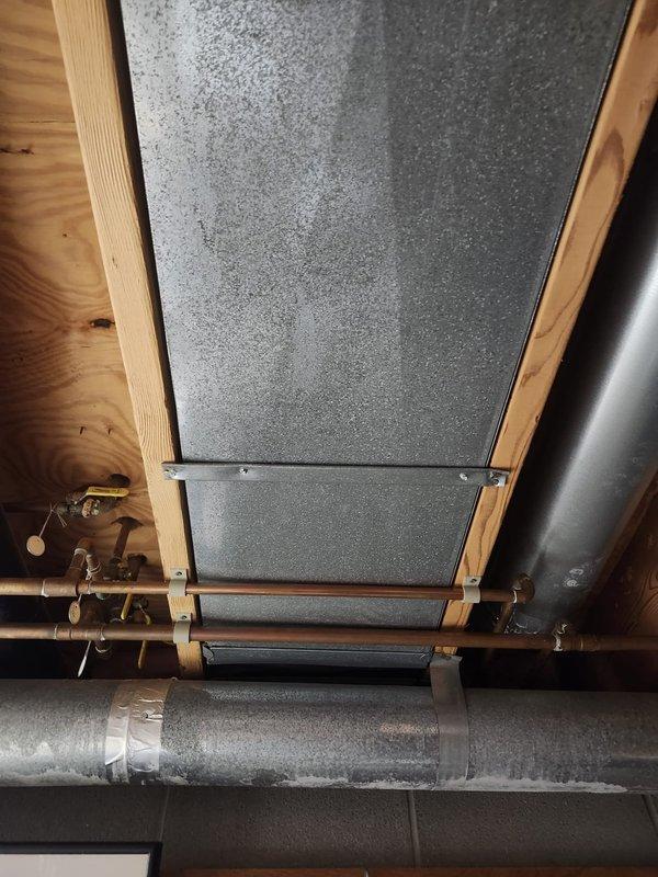 Completed full HVAC system installation consisting of two furnaces and two air conditioning units in residential basement location. Installed new ductwork including galvanized metal supply and return plenums, rigid rectangular trunk lines, and flexible duct connections routed through ceiling joists. Mounted furnace units with proper clearances, connected gas lines, electrical service, and integrated white-cabinet air treatment accessory for enhanced indoor air quality. Secured all ductwork with appropriate hangers and supports to wooden framing members, ensuring proper pitch and alignment throughout distribution system. Verified all equipment startup parameters, airflow measurements, and system functionality upon completion.