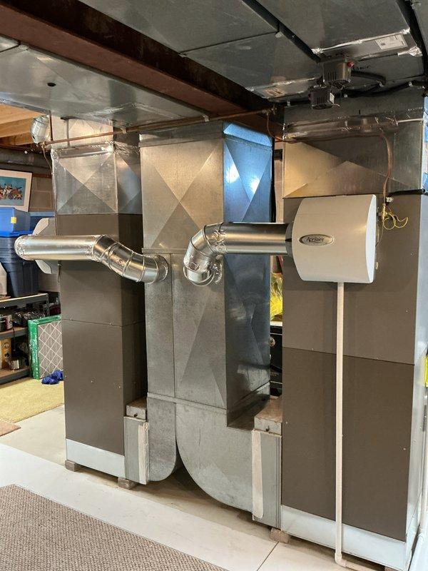 Completed full HVAC system installation consisting of two furnaces and two air conditioning units in residential basement location. Installed new ductwork including galvanized metal supply and return plenums, rigid rectangular trunk lines, and flexible duct connections routed through ceiling joists. Mounted furnace units with proper clearances, connected gas lines, electrical service, and integrated white-cabinet air treatment accessory for enhanced indoor air quality. Secured all ductwork with appropriate hangers and supports to wooden framing members, ensuring proper pitch and alignment throughout distribution system. Verified all equipment startup parameters, airflow measurements, and system functionality upon completion.