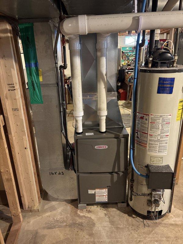 Completed furnace retrofit in basement mechanical room, installing new Lennox high-efficiency gas furnace with associated white PVC venting system routed vertically through ceiling. Integrated unit with existing ductwork infrastructure, including large-diameter supply plenum and 16x25 return air configuration. All electrical connections, condensate drainage, and combustion air venting installed per manufacturer specifications and local code requirements.