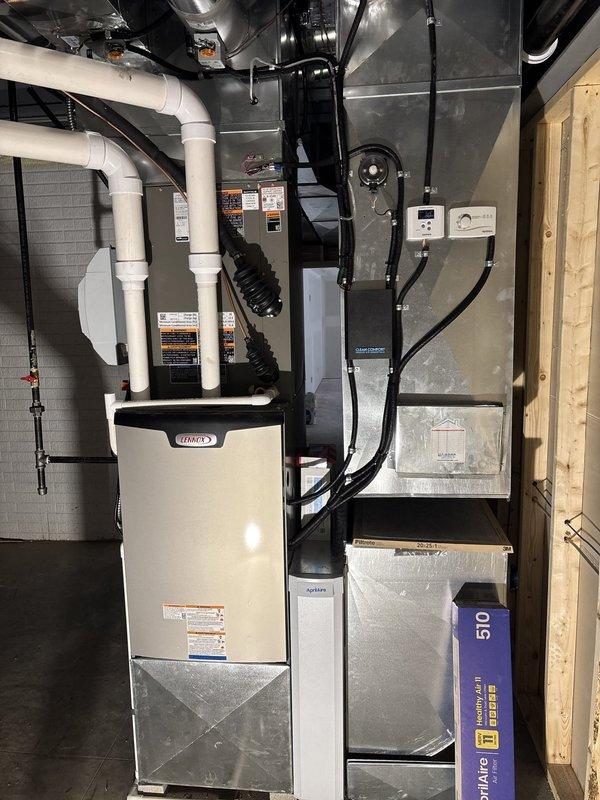 # HVAC New Construction Install

Completed full residential HVAC system installation in new construction basement mechanical room, including Lennox furnace unit with associated ductwork, PVC condensate drain lines, and wall-mounted humidifier. Installed black flexible and silver metal supply/return ductwork throughout the space, ran electrical conduit and wiring to connect system components, and secured all drain lines and piping to concrete block walls per code requirements.