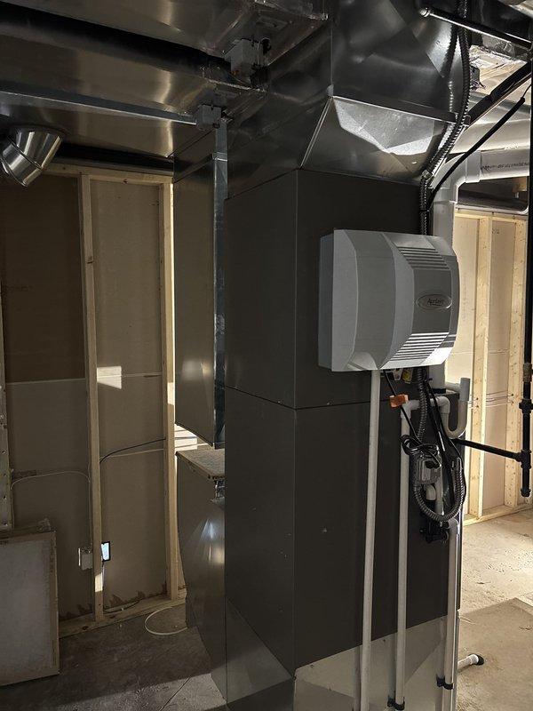 # HVAC New Construction Install

Completed full residential HVAC system installation in new construction basement mechanical room, including Lennox furnace unit with associated ductwork, PVC condensate drain lines, and wall-mounted humidifier. Installed black flexible and silver metal supply/return ductwork throughout the space, ran electrical conduit and wiring to connect system components, and secured all drain lines and piping to concrete block walls per code requirements.