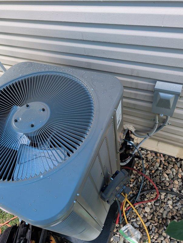 # HVAC Install - Complete System

Completed full furnace and air conditioning retrofit installation at residential property. Installed new outdoor condensing unit with heat pump capability on gravel pad with vibration dampening base against exterior wall. Unit features high-efficiency vertical fin condenser coil and top-discharge fan configuration. Ran and connected refrigerant line set using gray insulated copper tubing with proper brass compression fittings and black foam-insulated suction line to prevent condensation. Established all refrigerant piping connections to outdoor unit with proper flare fittings and torque specifications.

Performed system commissioning and startup procedures. Connected digital manifold gauges to service ports to verify refrigerant charge and system pressures. Monitored superheat and subcooling values to ensure optimal refrigerant charge per manufacturer specifications. Verified proper airflow through condenser coil and confirmed fan motor operation. Inst