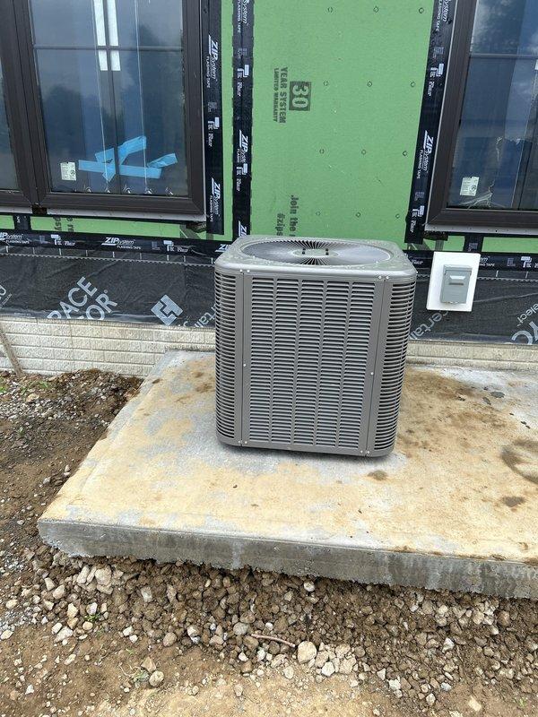 Completed site assessment and documentation for commercial HVAC new construction installation. Outdoor condensing unit successfully positioned on concrete pad with proper clearances maintained from building exterior, which features ZIP System sheathing and Andersen window installations currently in progress. Verified equipment placement, pad integrity, and electrical disconnect mounting in accordance with construction specifications for multi-unit residential project.
