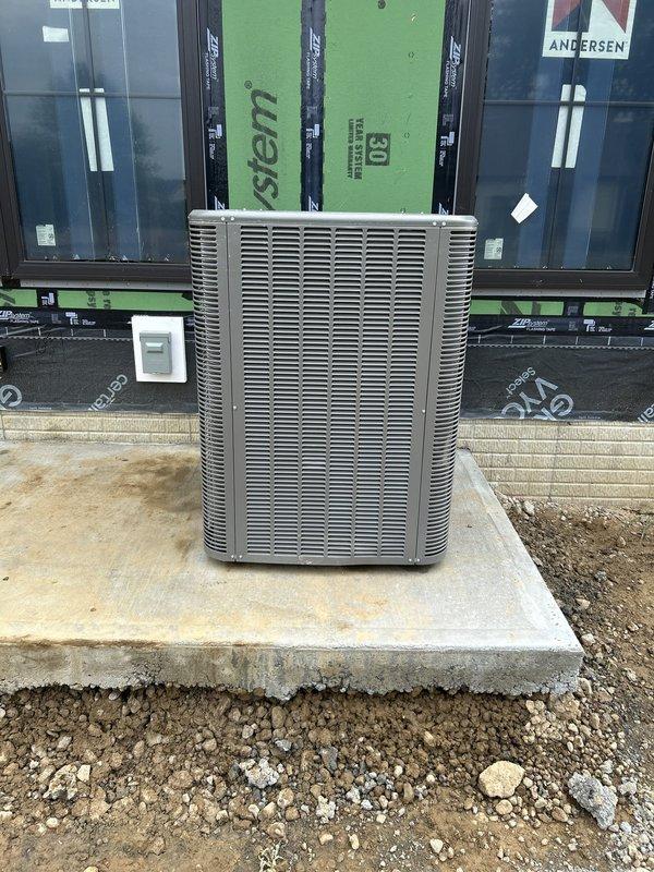 Completed site assessment and documentation for commercial HVAC new construction installation. Outdoor condensing unit successfully positioned on concrete pad with proper clearances maintained from building exterior, which features ZIP System sheathing and Andersen window installations currently in progress. Verified equipment placement, pad integrity, and electrical disconnect mounting in accordance with construction specifications for multi-unit residential project.