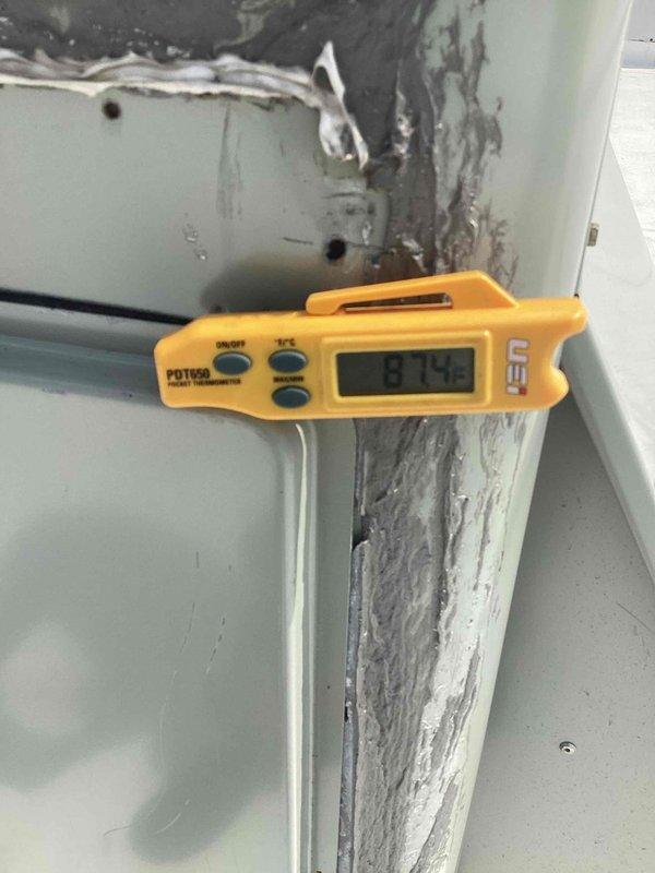 Responded to no cooling complaint in front area with afternoon cooling issues in back unit. Upon inspection, discovered severe heat damage and deterioration to ductwork components, with extensive charring and oxidation along panel seams and joints. Temperature reading of 87.4°F confirmed inadequate cooling performance. Inspected Trane RTU and found compromised air filter requiring replacement. Replaced allergen filter and assessed heat-damaged ductwork sections for necessary repairs to restore proper system operation and airflow distribution.