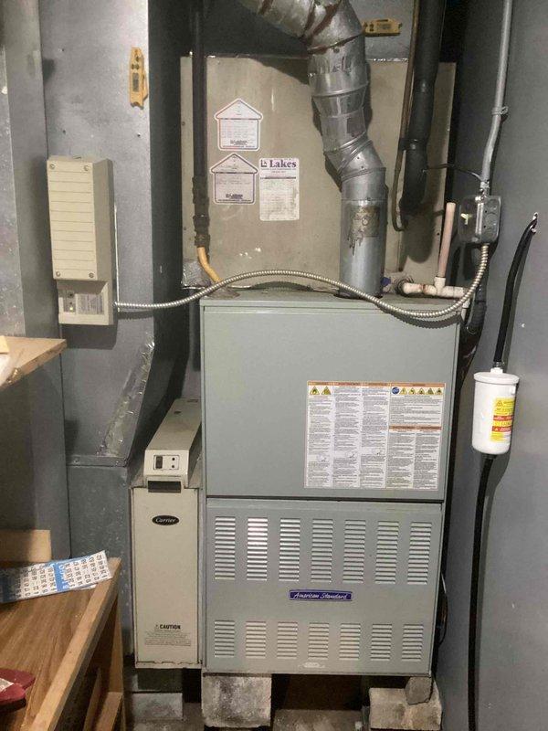 Responded to service call for non-functioning air conditioning system with reported indoor temperature of 80 degrees. Upon inspection, found American Standard furnace and Carrier air handler installation in basement utility area. Diagnosed electrical issue with transformer showing visible corrosion on mounting bracket and verified proper wiring connections to control components. Inspected ductwork, gas lines, and electrical conduit for proper installation and functionality. System restored to normal operation with proper cooling capacity achieved.