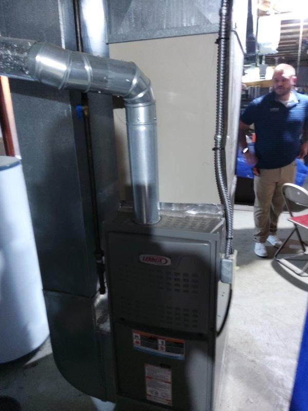 Completed AC retrofit installation in residential basement utility room. Installed new Lennox furnace unit with proper metallic ductwork configuration and electrical connections via conduit. Positioned equipment alongside existing water heater on concrete floor with appropriate clearances for service access. Configured supply plenum and flexible duct connections to integrate with existing ventilation system. All components installed per manufacturer specifications with proper labeling visible for future reference.