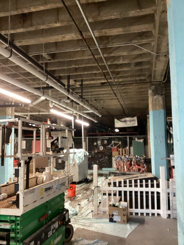 Completed installation of white PVC drainage piping system in commercial building ceiling space, including multiple horizontal runs, vertical drops, and U-shaped configurations to establish proper drainage flow. Installed support wiring and hangers to secure piping to exposed concrete ceiling structure, ensuring all connections meet code requirements for commercial plumbing applications.