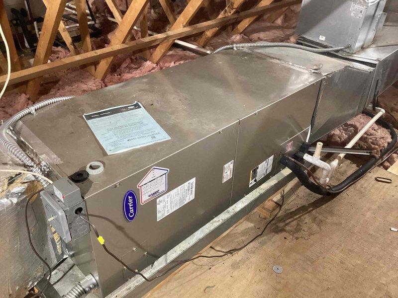 Responded to no cooling complaint on commercial heat pump system. Inspected Carrier air handler in attic space and outdoor condensing unit, verified all electrical connections, refrigerant lines, and ductwork connections. System evaluated and photographed for documentation purposes.