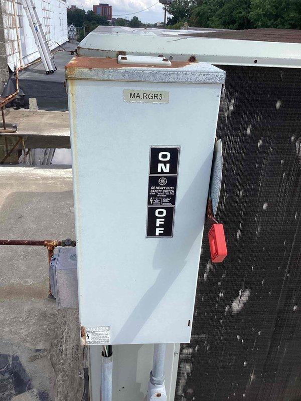 Responded to no cooling complaint in sanctuary area where unit attempted to start but produced clicking and buzzing noise without condenser fan operation. Found disconnect switch in OFF position as customer had de-energized unit. Inspected electrical components, control panel wiring connections, and disconnect box on rooftop unit. Verified proper wire terminations at terminal blocks and examined control board specifications and electrical ratings. Unit tagged and photographed for documentation purposes.
