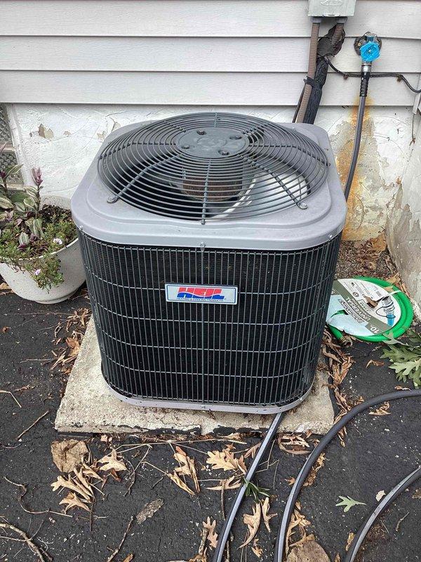 Responded to service call for loud clanging noise from operating air conditioning system. Upon arrival, performed visual inspection of outdoor condenser unit and indoor air handler components. Examined condenser unit exterior, noting accumulation of debris around base and unit operating components. Opened indoor air handler cabinet to inspect blower motor assembly, electrical connections, and internal mechanical components for source of reported noise. Documented equipment condition with photographs showing condenser installation, internal blower assembly, wiring configuration, and overall system components to assess potential causes of mechanical noise during operation.