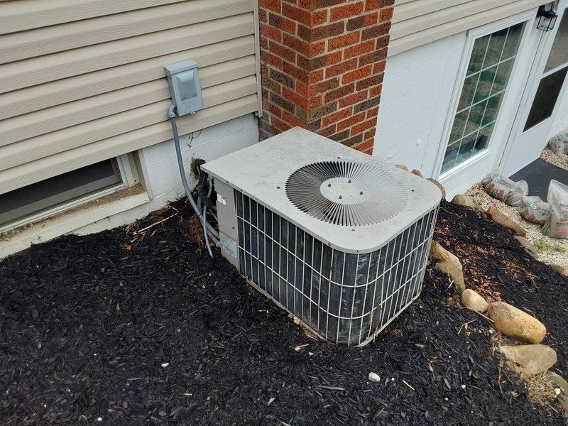 Completed full HVAC system replacement including installation of new furnace unit in basement utility area and outdoor condensing unit. Furnace installed against interior wall with proper ductwork connections and ventilation routing. Exterior condenser positioned on concrete pad with appropriate clearances from building structure, connected via refrigerant lines and electrical conduit to indoor unit. Electrical disconnect box mounted on exterior wall for service accessibility. All connections secured and system tested for proper operation.