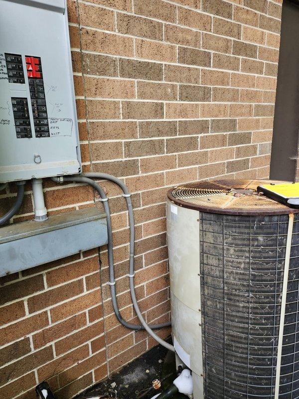 Completed full commercial HVAC system installation including furnace and air conditioning unit. Installed cylindrical condensing unit with top-discharge configuration against exterior brick wall, connected electrical disconnect box with proper conduit routing, and ran PVC condensate drain line. Updated electrical breaker panel with dedicated circuits for new HVAC equipment, implementing appropriate lock-out/tag-out safety devices on breaker panel for system protection. All equipment mounted securely to building exterior, electrical connections completed to code, and system tested for proper operation.