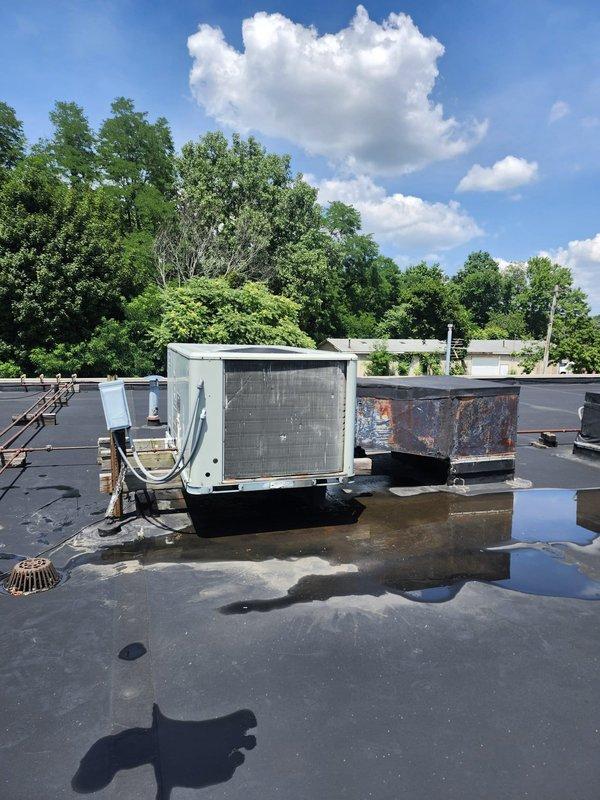 Conducted comprehensive estimate evaluation of commercial rooftop HVAC units. Assessed two RTU systems, documenting significant weathering and corrosion on exterior components, deteriorated electrical disconnect box with aged fuses and oxidized terminals, and standing water issues on roof membrane affecting equipment placement. Photographed equipment conditions including condenser coils, refrigerant lines, and electrical connections to support full system replacement recommendations.