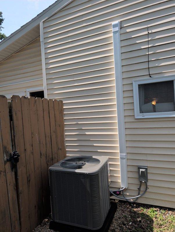 # AC Retrofit Installation

Successfully completed a comprehensive AC retrofit installation at a residential property. Removed existing air conditioning system and installed new outdoor condenser unit on prepared gravel base with proper clearances from structure. Unit positioned on exterior wall with beige vinyl siding, ensuring adequate airflow and accessibility for future maintenance. Mounted electrical disconnect box on exterior wall with appropriate conduit routing and secure wiring connections to comply with electrical codes.

Inside the basement mechanical room, installed new evaporator coil to match the outdoor condenser specifications. Integrated coil with existing air handler unit, ensuring proper refrigerant line connections and condensate drainage. Ran refrigerant lines between indoor and outdoor components through wall penetration, properly sealed and insulated to prevent energy loss and moisture issues.

Completed all electrical connections including power supply to conden