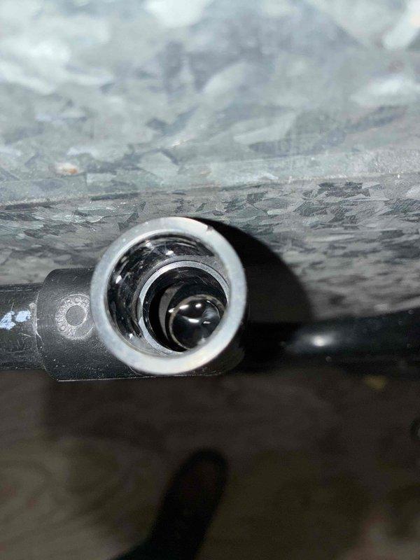 Responded to commercial A/C leak complaint and performed system inspection. Upon arrival, identified active refrigerant leak at evaporator coil connection point in air handler unit. Inspected multi-unit HVAC installation including stacked air handlers and ductwork assembly. Documented leak location with photographic evidence showing affected metallic cylindrical connection and surrounding insulation material. Verified leak source at concentric ring nozzle connection on evaporator coil inlet. Assessed overall system configuration including Carrier brand equipment, vertical ductwork routing, and associated piping. Recommended immediate refrigerant leak repair at coil connection point to restore system integrity and prevent further refrigerant loss.