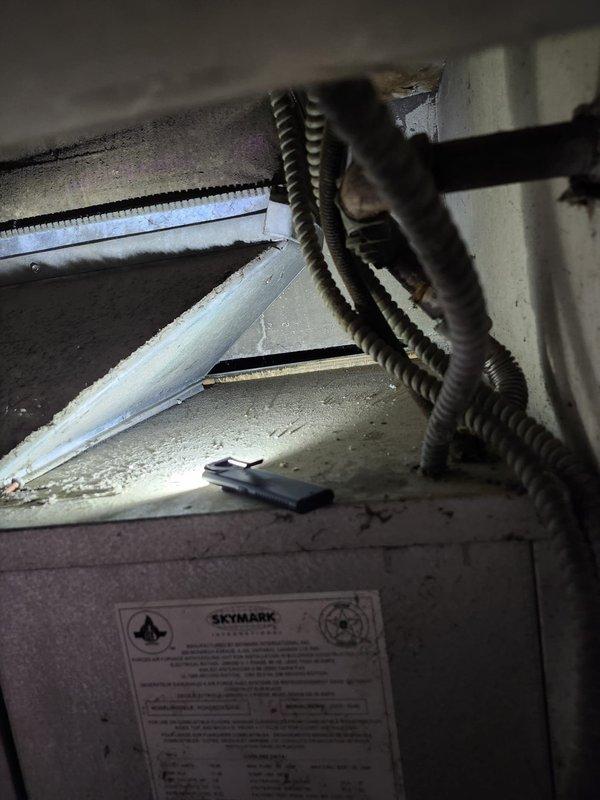 # AC Retrofit Installation

Completed full AC retrofit installation involving removal and replacement of existing air conditioning system and evaporator coil. Upon initial inspection, discovered extensive black mold contamination throughout the interior of the existing air handler cabinet, indicating prolonged moisture intrusion and poor system performance. 

Removed contaminated air handler unit and assessed installation area conditions. Prepared attic space for new equipment installation, ensuring proper clearances and access for future maintenance. Installed new Skymark brand air handler unit with factory-fresh evaporator coil in accordance with manufacturer specifications. Routed electrical conduit and wiring to power supply, securing all connections with appropriate clamps and supports.

Connected refrigerant lines to outdoor condensing unit and evaporator coil, ensuring proper insulation on suction line to prevent condensation. Installed new condensate drain system with proper pi