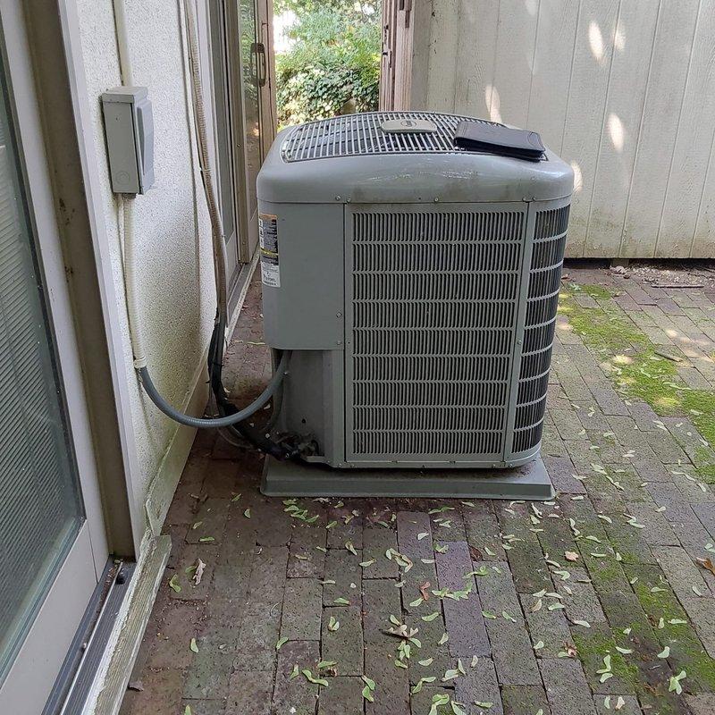 Completed full HVAC system retrofit including furnace and air conditioning replacement at residential property. Installed new outdoor condensing unit on existing brick paver pad with proper electrical conduit and refrigerant line connections to exterior wall penetration. Replaced indoor furnace unit in basement utility area with copper refrigerant lines routed vertically and PVC condensate drain properly installed. All equipment secured, connections tested for leaks, and system commissioned to manufacturer specifications.
