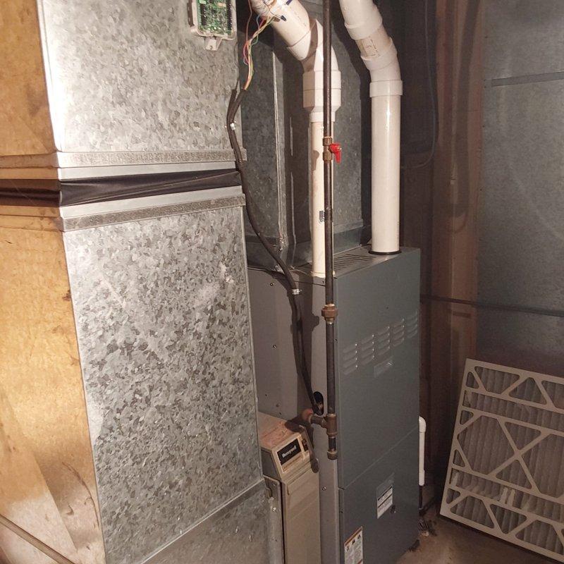 Completed comprehensive AC retrofit installation including replacement of outdoor condenser unit and indoor air handler system. Installed new HVAC equipment in basement utility area with proper ductwork connections, PVC condensate drainage lines with safety valve, and electrical conduit routing. Positioned outdoor condenser unit against exterior brick wall with refrigerant line connections and proper clearances. All components tested and verified operational upon completion of installation.