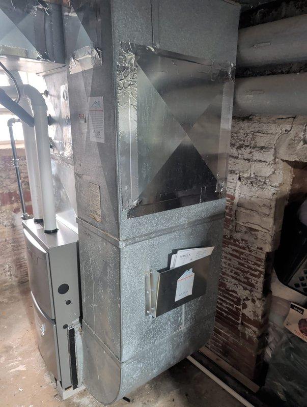 Completed furnace retrofit installation in residential basement utility space. Installed new gray Lennox furnace unit with dual white PVC intake and exhaust venting system running vertically from top of unit. Connected copper refrigerant lines, integrated with existing green air handler cabinet, and installed galvanized metal ductwork with proper sealing and support. All manufacturer specifications verified, digital control panel programmed and operational, system tested and confirmed functioning within normal parameters.