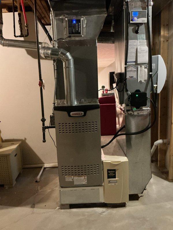 Completed AC retrofit installation at residential property. Installed new Lennox outdoor condensing unit on platform pad with gravel base against exterior wall, including electrical disconnect box and conduit connections. Interior installation included new evaporator coil integrated with existing Lennox furnace system in basement mechanical room, with proper refrigerant line connections and ductwork modifications to main plenum. System tested and verified operational with all electrical connections secured and refrigerant charge confirmed to manufacturer specifications.