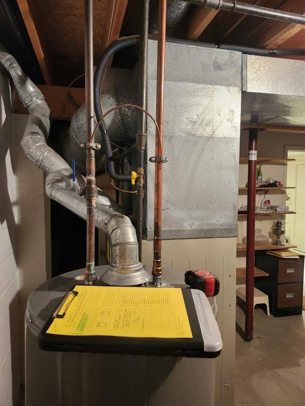 # HVAC Install - Complete System

Completed full furnace and air conditioning system retrofit in residential basement utility area. Installed new gray metal furnace/air handler unit with associated metal ductwork and flexible corrugated connections. Routed black conduit and piping from furnace to accommodate new system requirements. Connected metallic flexible ductwork with proper insulation wrapping to ceiling-mounted distribution system. Integrated new HVAC equipment alongside existing cylindrical water heater, ensuring proper clearances and access for future maintenance. Installed copper piping with expansion loop configuration and black supply lines to support system operation. All mechanical connections secured to exposed wooden framing per code requirements. System tested and verified operational upon completion.