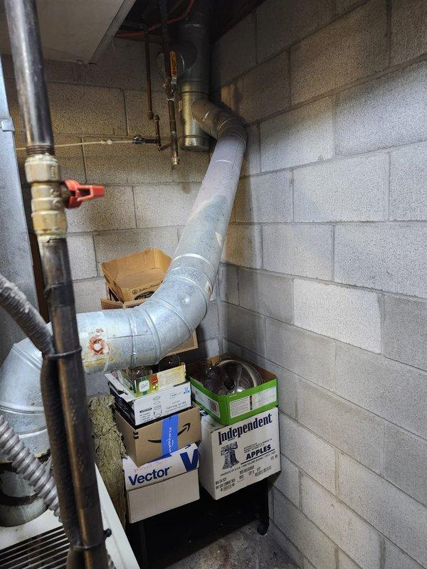 Completed furnace retrofit installation in basement mechanical room. Installed new beige-cabinet furnace unit with associated ductwork connections, including reflective foil-wrapped supply plenum and metal ductwork routing. Connected white PVC condensate drainage and venting piping to unit, installed digital control panel on wall, and verified all connections for proper operation.