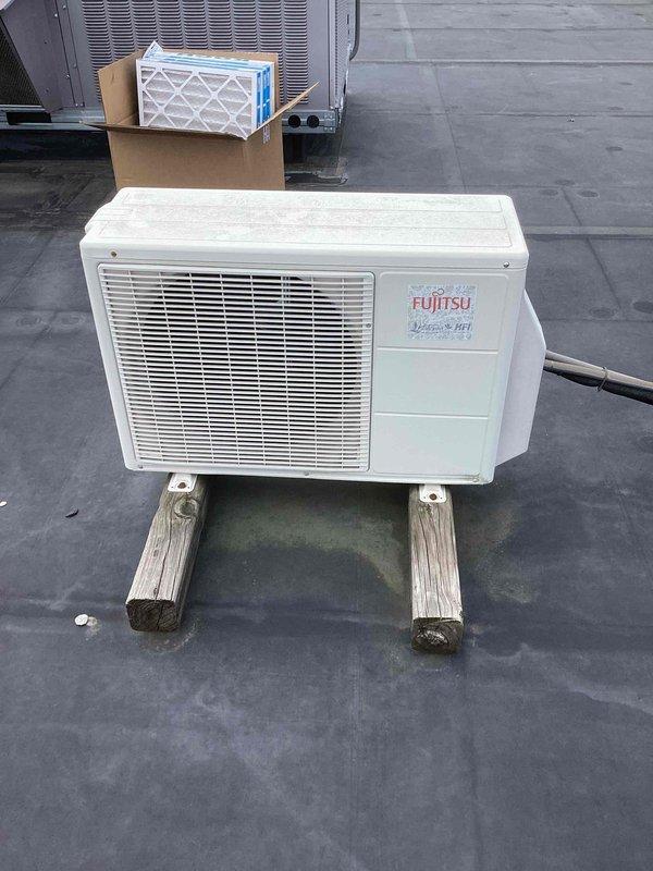 Completed routine commercial cooling maintenance on Fujitsu mini-split system. Inspected outdoor condenser unit on rooftop and indoor wall-mounted air handler, verified operational status of both components, documented equipment condition with photos showing unit positioning and general wear patterns on installation materials.
