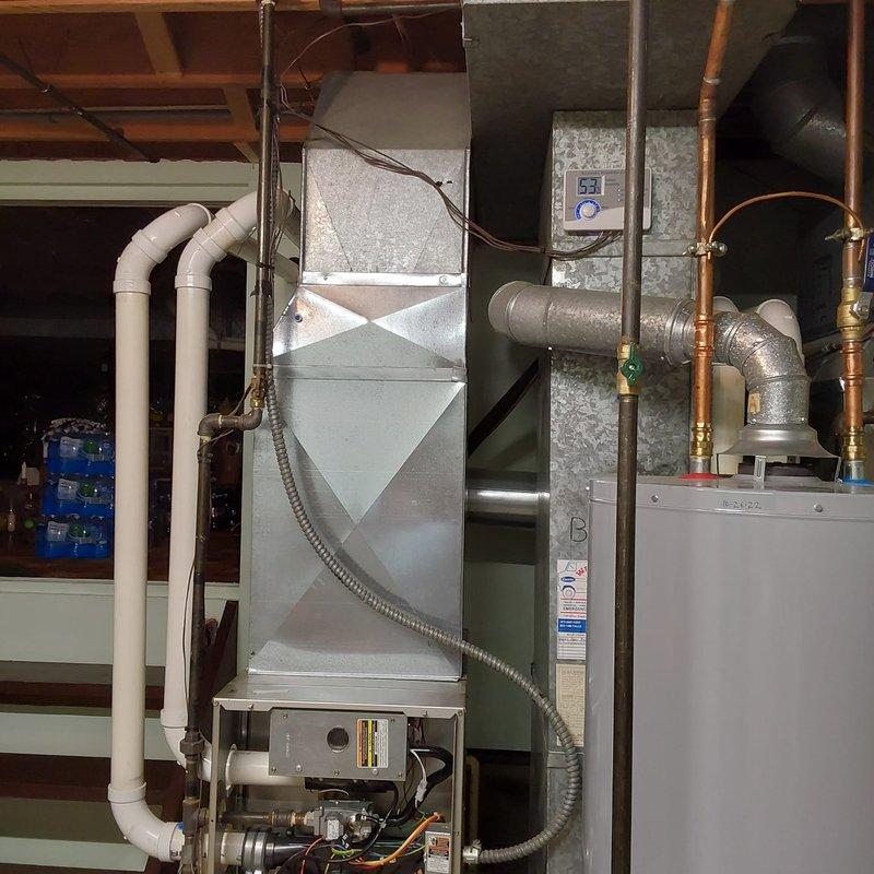Completed furnace retrofit in residential basement mechanical room, installing new Carrier brand air handler unit to replace existing heating equipment. Installation included proper connection of ductwork with metallic plenum and flexible duct connectors, integration with existing water heater and plumbing systems, and verification of all electrical controls and thermostat functionality.