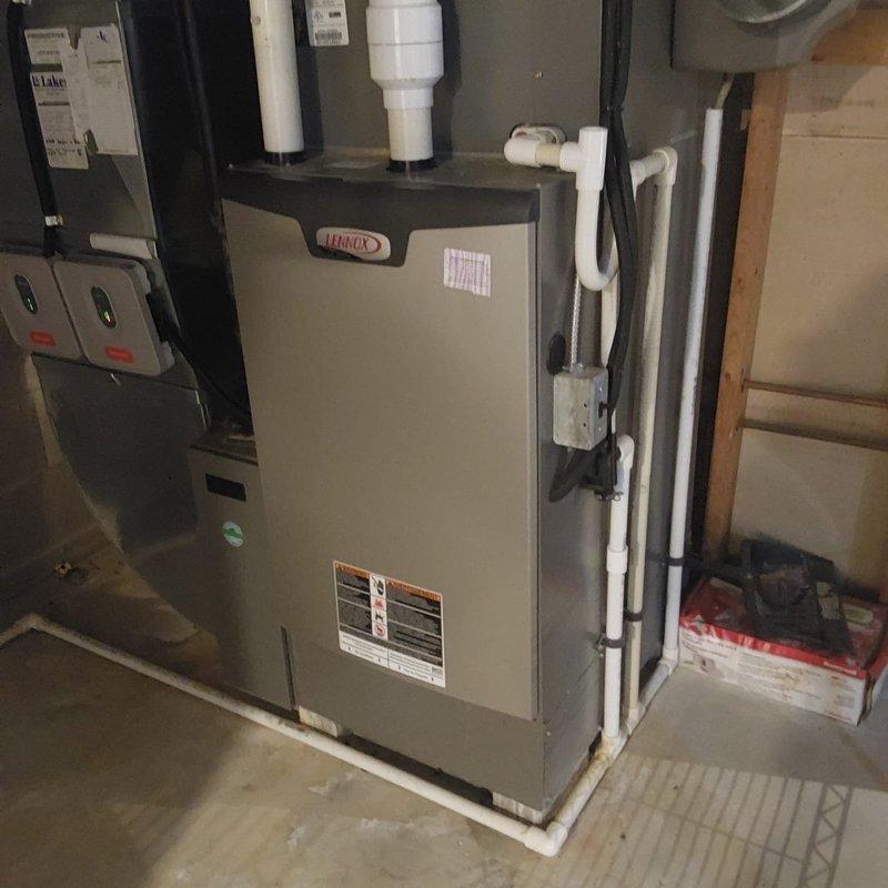 Completed full HVAC system retrofit including outdoor condenser unit and indoor Lennox furnace installation. Positioned new condenser on concrete pad blocks with proper clearance from building, installed refrigerant line set with secure fastening, and ran electrical conduit to wall-mounted junction box. Inside mechanical room, installed new Lennox furnace with complete PVC venting system, condensate drainage piping, and electrical connections to code-compliant control panels.