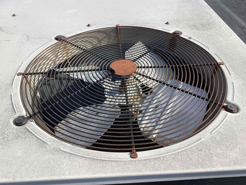 Replaced failed condenser fan motor and blade assembly on commercial HVAC unit. Removed existing motor with corroded mounting hardware, installed new Hartzell fan motor with three-blade assembly, and secured protective wire grille. Unit tested and operational upon completion.