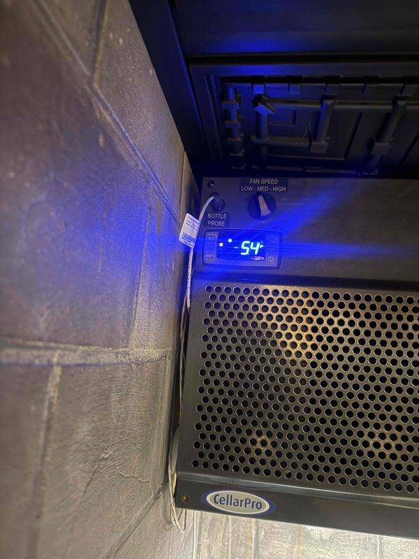 # Wine Room Mini Split Service Call

Responded to service call for 8-year-old CellarPro wine room cooling unit not maintaining proper temperature. Upon arrival, found unit operational but displaying 54°F on digital control panel. Performed diagnostic testing and temperature verification using calibrated digital thermometer, which recorded 111.1°F at the supply air outlet, confirming significant cooling deficiency. Unit showed no obvious signs of mechanical failure, with control panel illuminated and fan operation functional across all speed settings (LOW, MED, HIGH). Documented equipment condition and temperature readings via photographs for service records. Based on age of system and observed performance issues, recommended further diagnostics to determine root cause of cooling loss, which may include refrigerant charge verification, compressor function testing, or potential component failure in the refrigeration circuit.