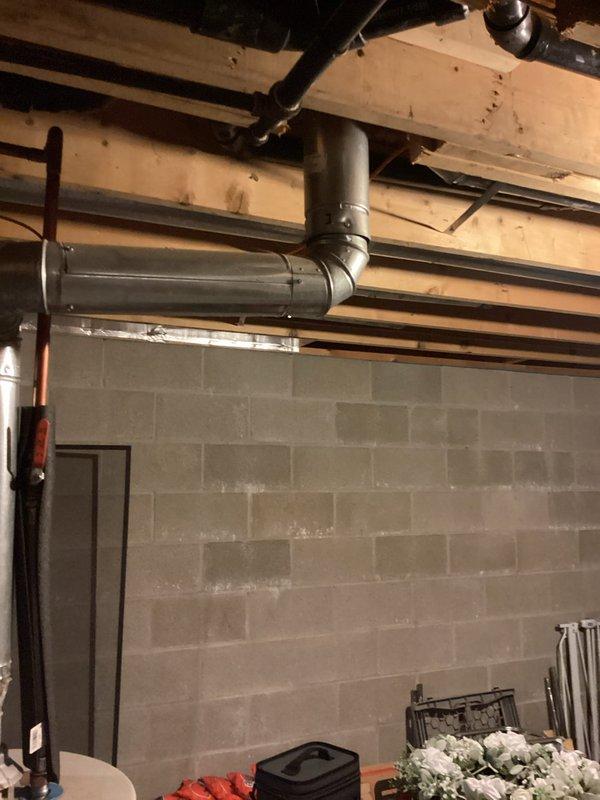 Responded to service call for water heater replacement in residential basement utility area. Upon arrival, assessed existing white cylindrical tanked water heater and surrounding plumbing connections. Completed full replacement of water heater unit, including disconnection and removal of old unit, installation of new tanked water heater, and reconnection of all supply lines, drain valves, and venting systems. Verified proper flue pipe connections to existing ductwork and ensured all metal piping connections at top of unit were secure and code-compliant. Tested water heater operation and confirmed system functionality before completing service.